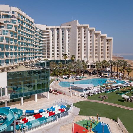ليوناردو كلوب هوتيل البحر الميت - شامل كلياً نيفيه زوهار المظهر الخارجي الصورة The image shows a large hotel complex alongside a pool area. The hotel features modern architecture with multiple levels and numerous balconies. In front of the hotel, there is a recreational area with a swimming pool, water slides, and lounging chai